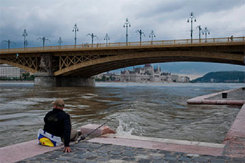 Horgász a Duna-parton egy budapesti híd közelében, felhős időben