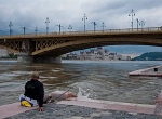 Horgász a Duna-parton egy budapesti híd közelében, felhős időben